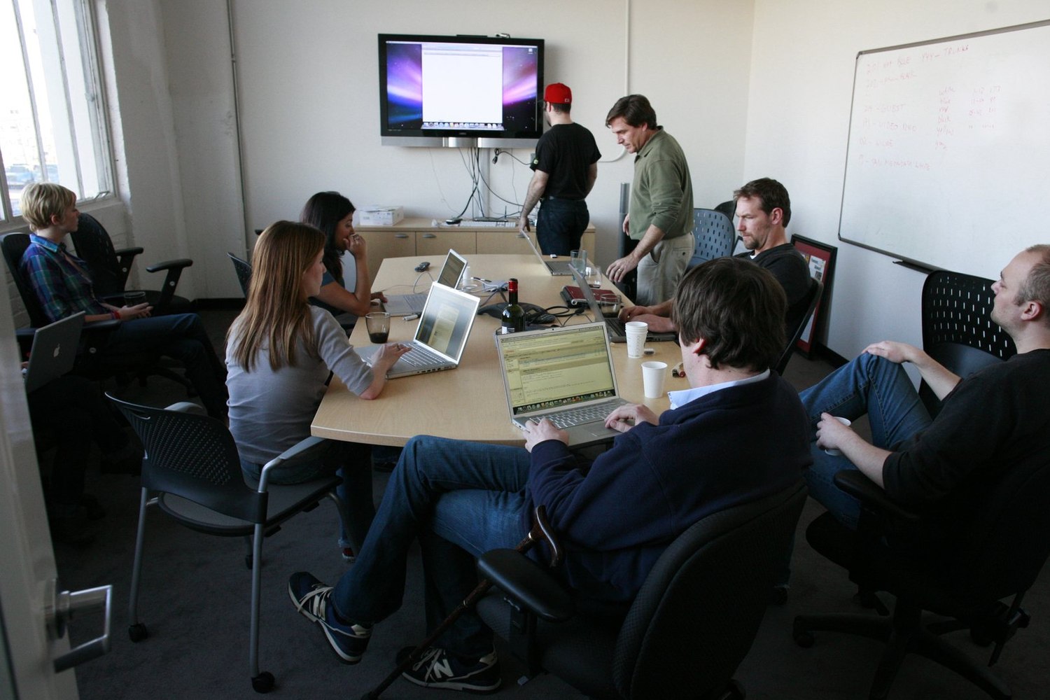 Colleagues collaborating around laptops at a table